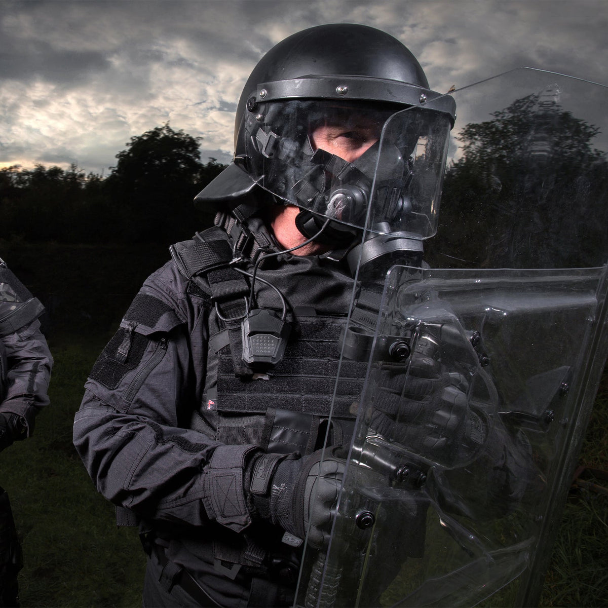 Medium shot, 3/4 view of a riot control police officer wearing a TAPR mask using the MSA gallet adapter kit attached to a riot helmet.